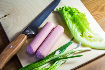 Products on a cutting board salad, onion, and knife