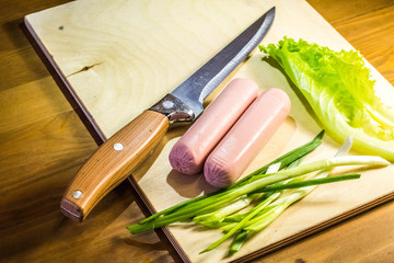 Products on a cutting board salad, onion, and knife