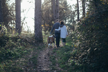 Naklejka na ściany i meble Young couple enjoying nature outdoors together with their Saint Bernard puppy. 