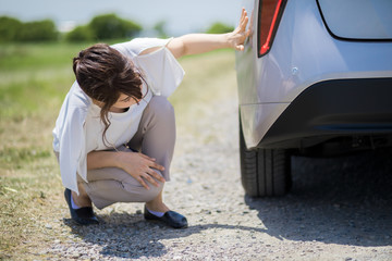 young woman checking under a vehicle.