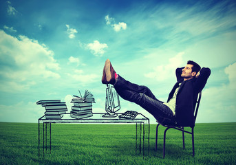 business man relaxing at his desk outdoors in the middle of a green meadow