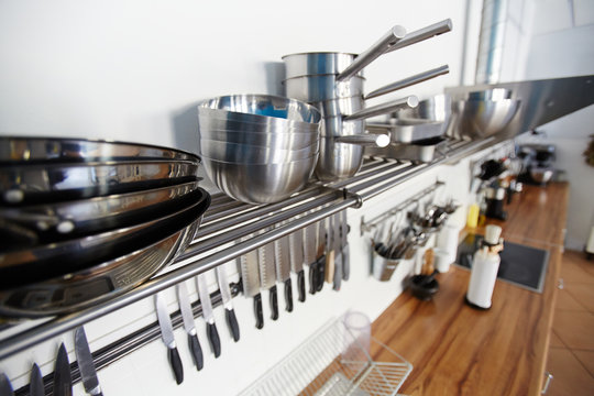Bowls and saucepans on metallic shelf along wall