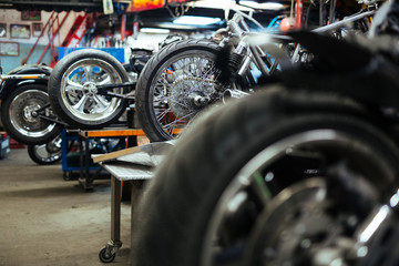 Fototapeta premium Background image of several motorcycles on stands in repair shop with back wheels in row