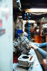 Closeup portrait of modern tattooed mechanic fixing broken  parts at table in  workshop