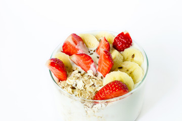 Light healthy breakfast - homemade yogurt with oat flakes strawberry and banana and flax seeds in a glass beaker on a white background