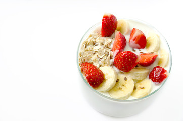 Glass beaker filled white homemade yogurt with oat flakes strawberry, banana, flax seeds on a white background. Copy space.