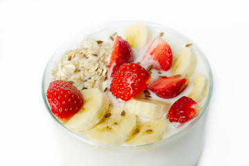 White yogurt with strawberry, banana, oat flakes, flax seeds on a white background sprinkled with flax seeds close-up on a white background..