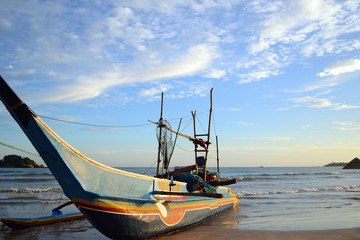 Traditional fishing boat of Sri Lankan fishermen moored on the shore of the ocean