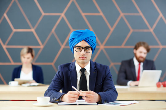 Arabian Man In Suit And Turban Looking At Camera At Workplace