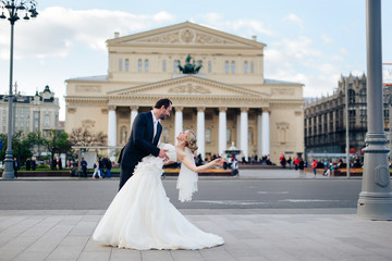 Beautiful wedding couple in Moscow, the bride and groom in a white dress in the street on the background of the Bolshoi Theater
