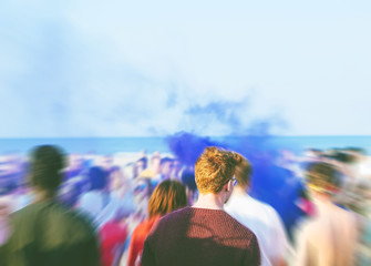 Young multicultural people dancing at a beach party with a blue color light of smoke in the...