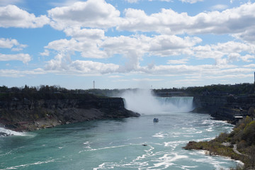 Niagara Falls Horseshoe waterfall on bright spring day with clouds and blue sky as seen from Ontario, Canada