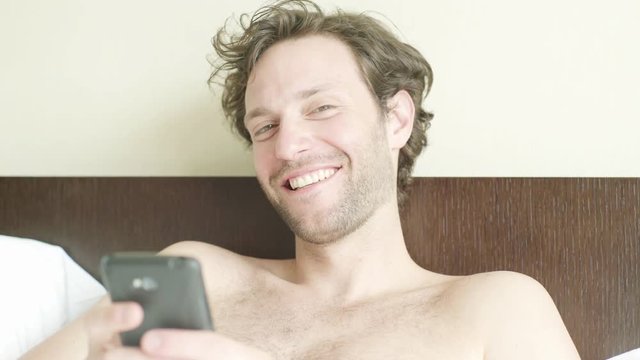 Man lying in bed looking at smart phone