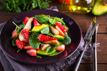 Healthy salad plate with avocado, strawberry, chicken and spinach on wooden background close up. Food and health. Clean eating.