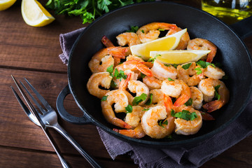 Shrimp Scampi traditional dish on wooden background close up. Shrimp fried in garlic batter with lemon and parsley. Healthy food. Clean eating.