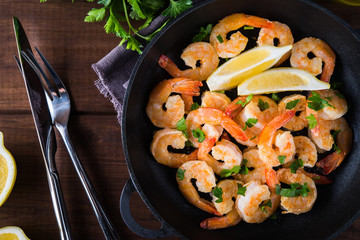 Shrimp Scampi traditional dish on wooden background top view. Shrimp fried in garlic batter with lemon and parsley. Healthy food. Clean eating.