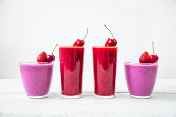 Cherry and blueberry smoothie and tasty summer berries on white wooden table. Fresh natural milkshake