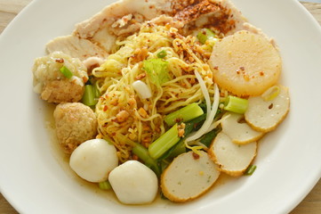 dried spicy Chinese egg noodles topping fish and shrimp ball with slice boiled pork on plate