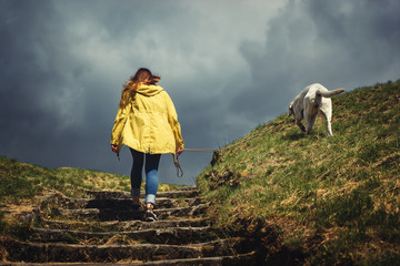 Junge frau und labrador retriever hund welpe gehen während eines Sturms im Herbst spazieren
