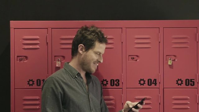 Man standing in front of lockers using smart phone