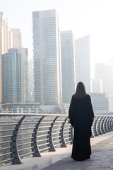 Woman in an abaya on a boardwalk.