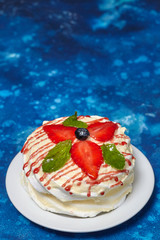 White creamy round cake with strawberries and mint on plate