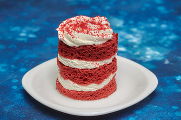 Round red velvet cake with cream on white plate