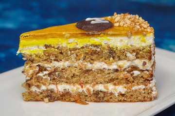 Piece of carrot cake with icing and walnut on plate