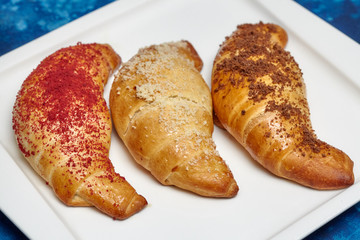 Three fresh buttery croissants on blue background