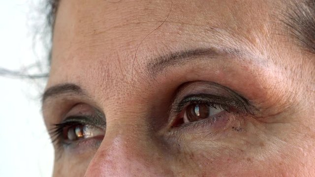bags of blinking eyes with one hair on wrinkled forehead of mature Caucasian woman with Arabic and Middle Eastern somatic traits