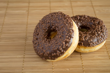 Chocolate donuts on the light brown wooden background