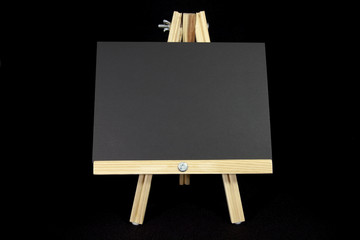 Easel with blank black card on black background. Copy space.