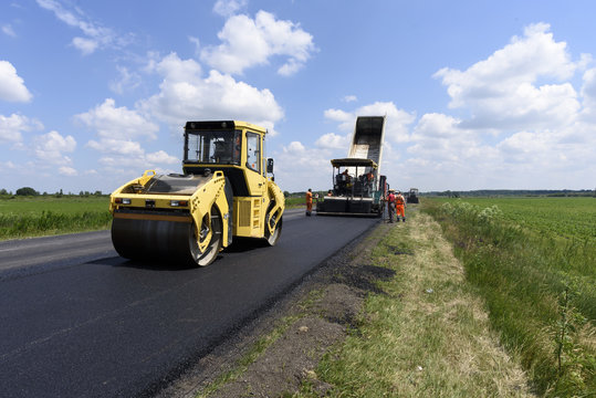 Yellow Roller And Workers Pave A New Road