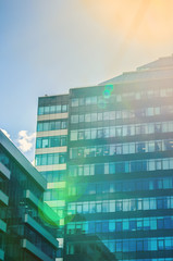 The building is a business center glass with green and blue windows, sunlight and glare