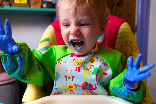 Caucasian Toddler Boy Wearing a Smock Mixes, Plays with and Finger-paint's on White Paper