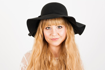 Closeup portrait of cute young woman with long blonde hair in floppy hat smiling