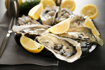 Tasty fresh oysters with juicy sliced lemon on plate. Aphrodisiac food for increasing sexual desire