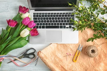 Photo sur Plexiglas Fleuriste Belles fleurs et ordinateur portable sur le lieu de travail du fleuriste