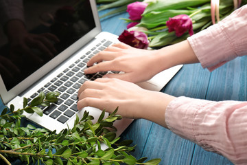 Female florist with laptop and flowers on wooden table