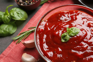 Delicious ketchup in bowl with ingredients, closeup