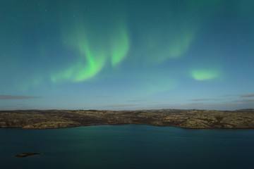 Fototapeta na wymiar The Aurora in the sky above the hills and water on a moonlit night.