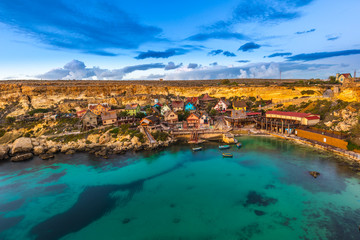 Mellieha, Malta - The famous Popeye Village at Anchor Bay at sunset with amazing colorful clouds and sky