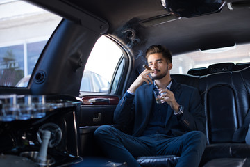 Young businessman enjoying cigar in limo