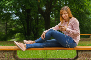Obraz premium Young woman texting on smart phone outdoors