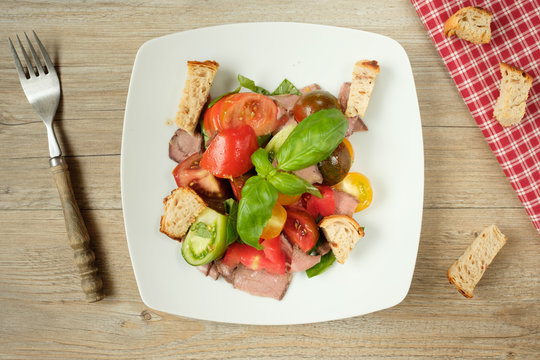 Salat mit Tomaten, Roastbeef, Brot und Basilikum