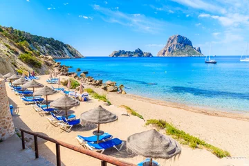Fotobehang Uitzicht op het strand van Cala d& 39 Hort met ligbedden en parasols en prachtig azuurblauw zeewater, Ibiza-eiland, Spanje © pkazmierczak