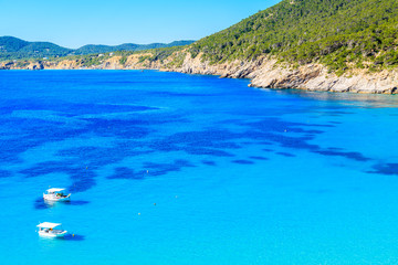 Fishing boats on blue sea water of Cala San Vicente bay, Ibiza island, Spain