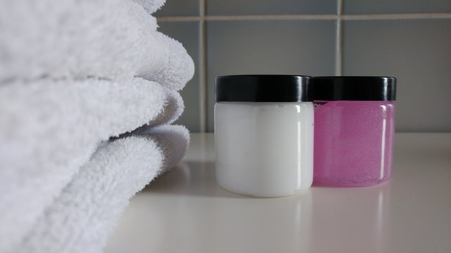 White Towels and Cosmetic products in tiled Bathroom