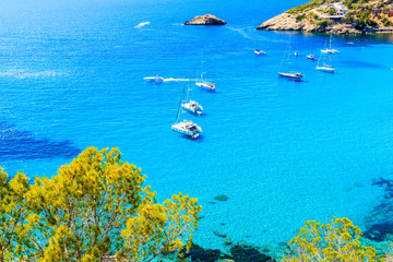 Catamaran boats on Cala d'Hort bay with beautiful azure blue sea water, Ibiza island, Spain