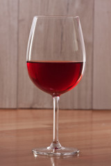 Red wine in a glass. A single glass. Colorful background. Wine-making. Reflection from a glossy surface.
